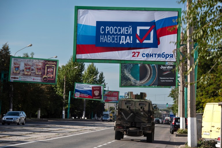 A military vehicle drives along a street with a billboard reading "With Russia forever, September 27" prior to a referendum in Luhansk, Luhansk People's Republic controlled by Russia-backed separatists, eastern Ukraine.