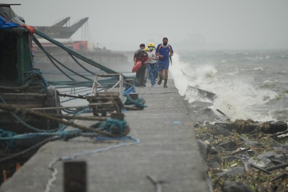 Rescuers run as waves crash on the walkway as they check on residents in a seafront slum in Manila