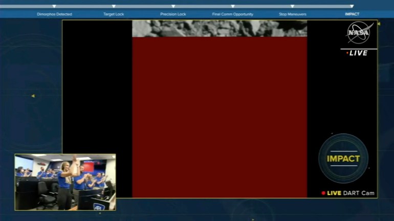 The feed breaks into a red screen as the DART hits the asteroid. A small box on the left shows NASA scientists in the control room applauding the mission
