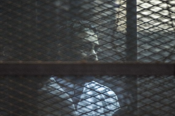 Alaa Abdel Fattah stands in a cage during a verdict hearing over an unauthorised street protest in 2013, in a courtroom in Cairo