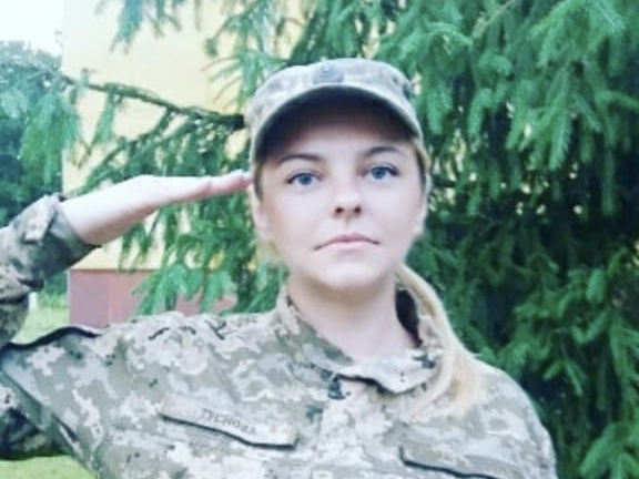 Anna in army uniform and cap, saluting.