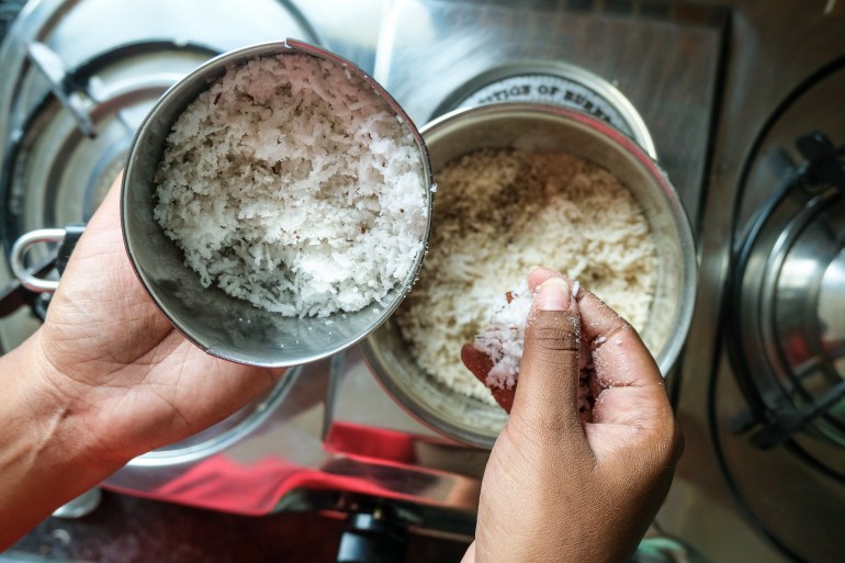 A photo of someone's hands as they add coconut to rice