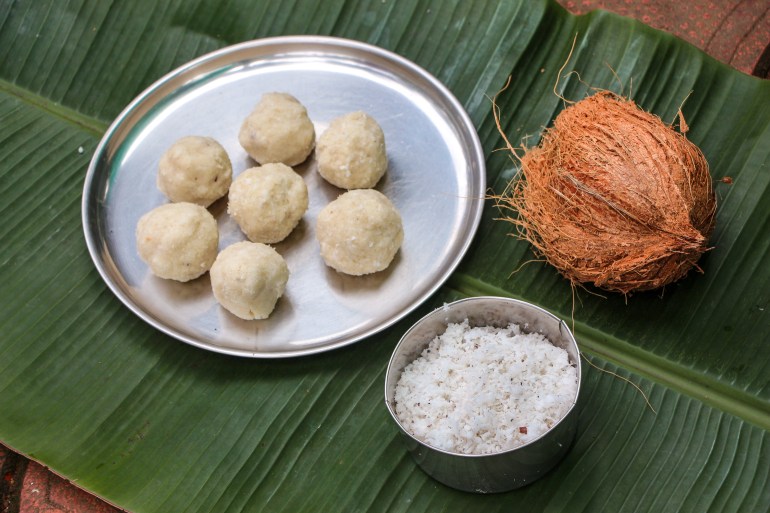 On a banana leaf is a coconut, a bowl of shredded coconut and a tray of bath aggala