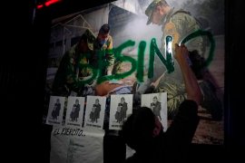 A protestor spray paints a picture of a member of the military