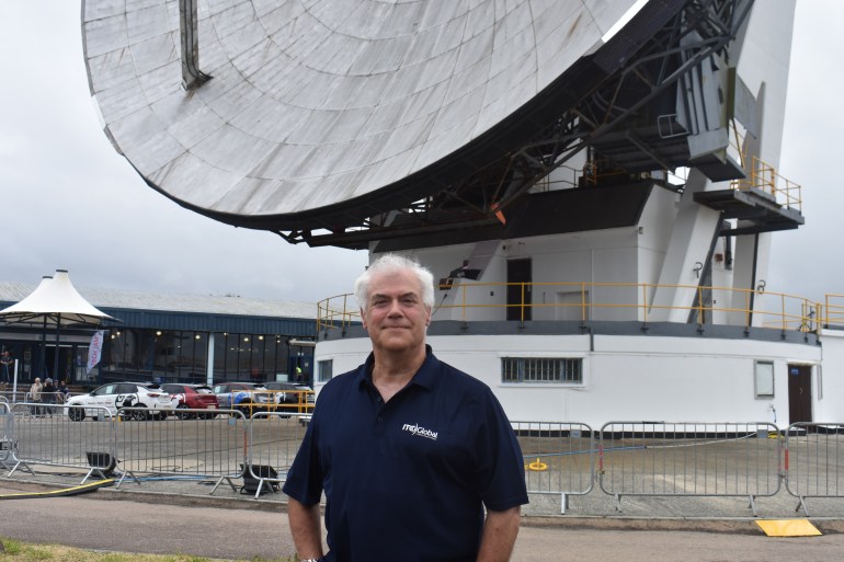 A photo of Simon Rodda standing outside in front of a large satellite.