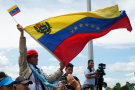 A man holds a Venezuelan flag during a ceremony to mark the reopening of the border between Colombia and Venezuela on September 26, 2022 [Fernando Vergara/AP Photo]