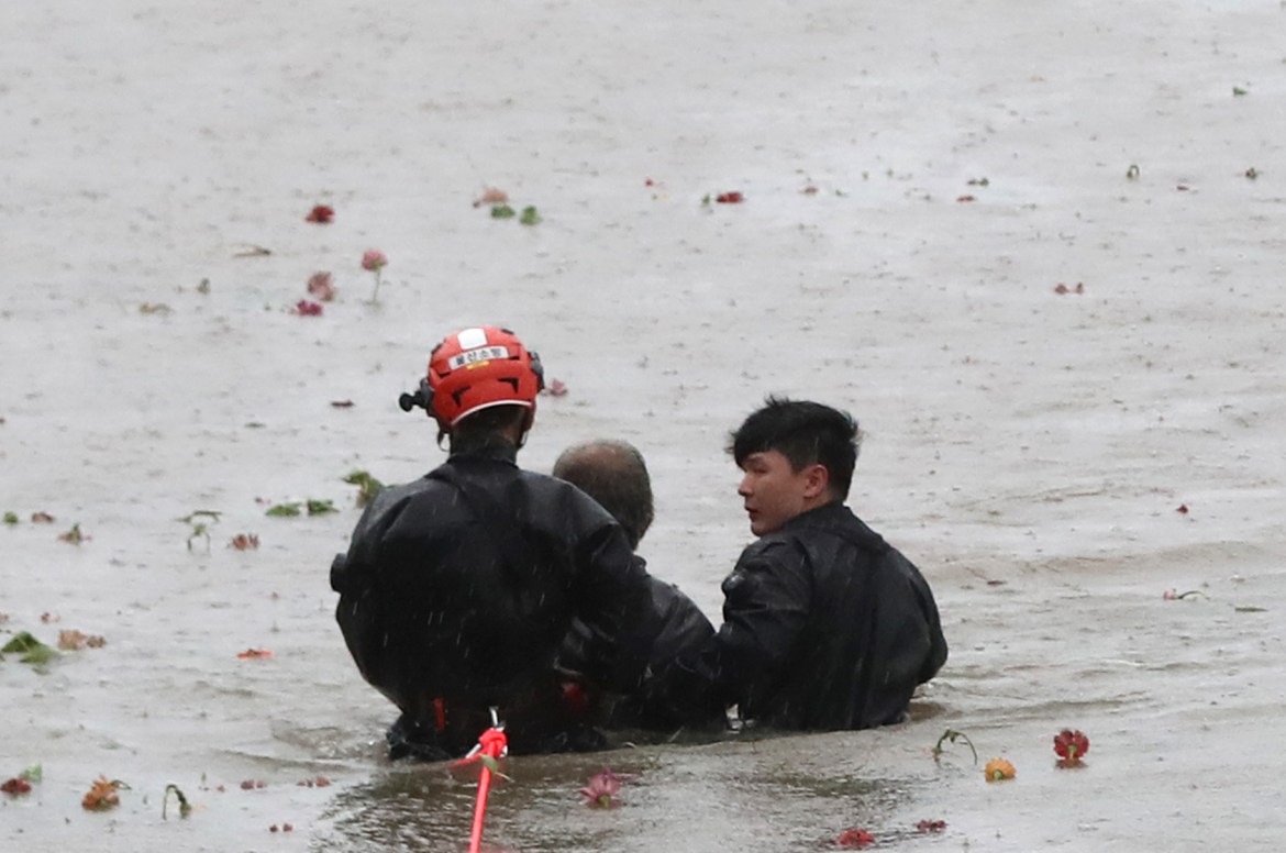 A stranded resident is rescued by workers along the Taehwa River