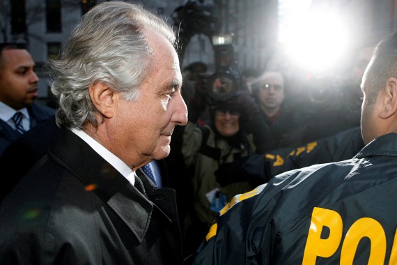 Disgraced financier Bernard Madoff is escorted by police and photographed by the media as he departs U.S. Federal Court after a hearing in New York