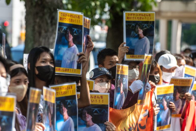 Protesters hold up photos of Toru Kubota as they call for his release
