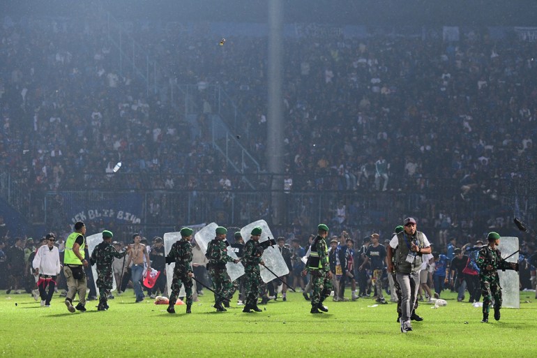 This October 1, 2022 photo shows members of the Indonesian military securing the field after the football match between Arema FC and Persebaya Surabaya at Kanjuruhan Stadium in Malang, East Java.