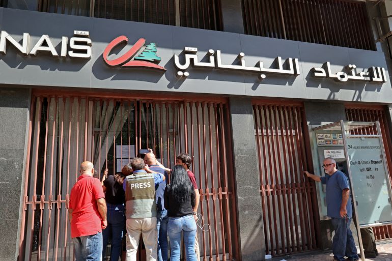 Lebanese security forces and press stand outside a branch of Credit Libanais bank held-up by an angry depositor demanding access to his savings, in the capital Beirut's southern suburb of Haret Hreik on October 5, 2022. - Banks in the country, mired in an economic crisis for more than two years, partially reopened last week under strict security after a week-long closure following a slew of heists by customers desperate to access their money. (Photo by ANWAR AMRO / AFP)
