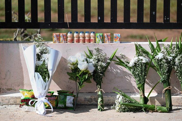 Bouquets of flowers and children's drinks are placed outside a nursery in Thailand on October 7 2022, the day after a mass killing by a former police officer in northeastern Nong Bua Lamphu province [AFP/Manan Vatsyayana]