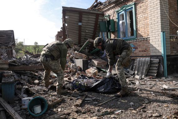 Ukrainian service members carry the body of a civilian from the rubbles of a destroyed house following shelling in Yakovlivka, Donetsk, Ukraine.