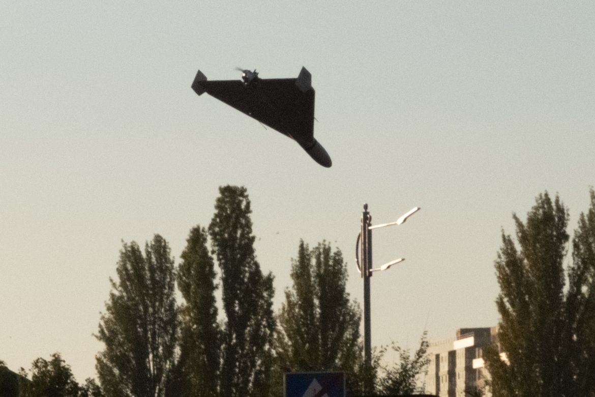 A drone is seen approaching for an attack in Kyiv, flying in above some trees