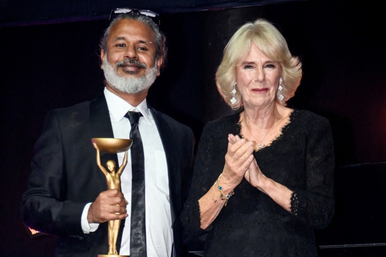 Sri Lankan writer Shehan Karunatilaka poses next to Britain's Queen Camilla, holding the Booker Prize gold trophy.