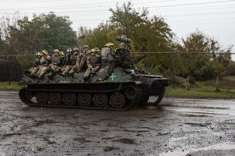 Ukrainian servicemen stand on an armoured personal carrier (APC) near Borivske, Kharkiv region