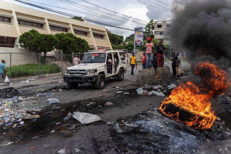 A car drives by burning tyres during a demonstration in Haiti