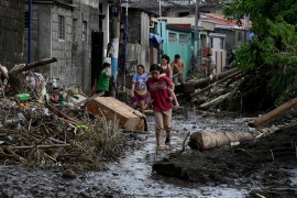 A woman walks along a mud and debris covered street in Cavite after Tropical Storm Nalgae hit the Philippines.