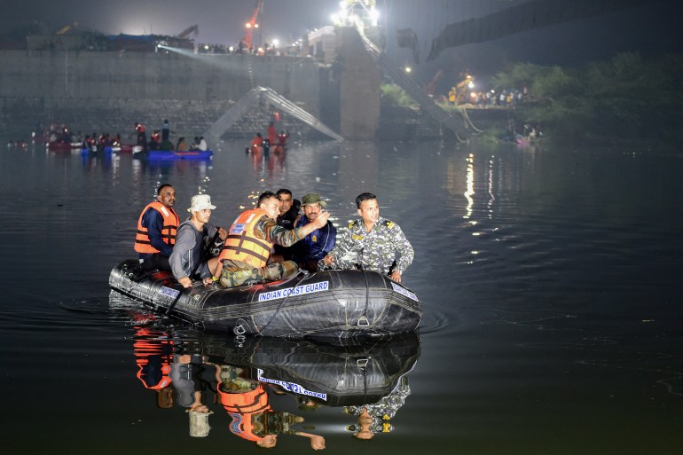 A boat with Indian rescue personnel conduct search operations after a bridge across the river Machhu collapsed in Morbi