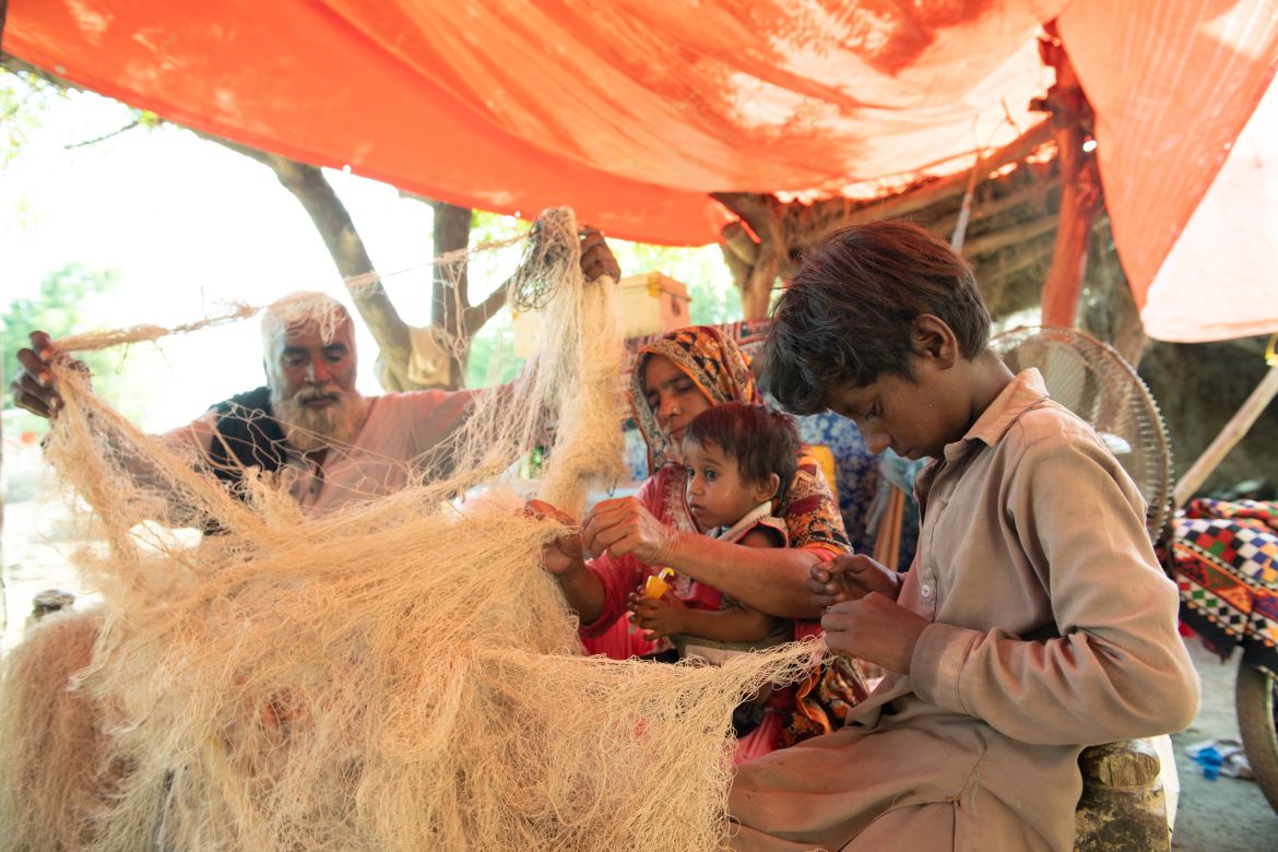 Muhammad Kasim, his wife, and eldest son repair fish nets