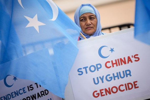 A woman in a pale blue headscarf joins a rally outside the White House carrying a sign reading: Stop China's Uyghur Genocide