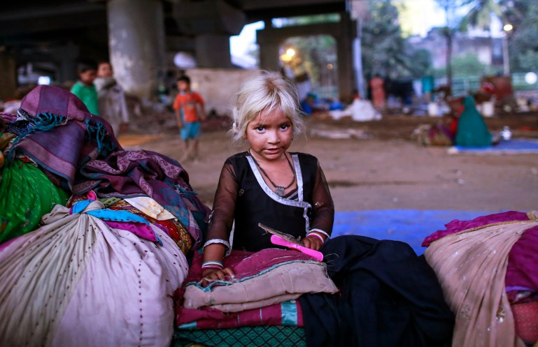 Five-year-old Nasreen rests with her family's belongings as she plays under a flyover in Mumbai January 19, 2015