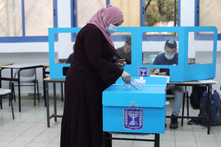 An Arab-Israeli woman wearing a protective face mask casts her ballot as she votes in Israel's general election, in Kafr Manda, northern Israel March 23, 2021