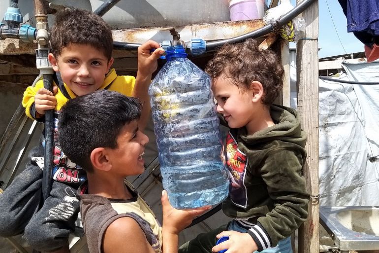 A Syrian refugee child holds a water bottle at an informal tented settlement in Akkar, Lebanon.