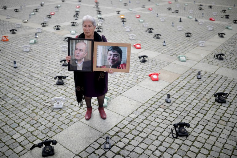 Fadwa Mahmoud holds portraits of her son and husband, who disappeared in 2012, as around 300 landline telephones placed by Syrian families stand at the Bebelplatz as a call to governments to do more to seek information about detained people in Syria, in Berlin, Germany August 28, 2021. REUTERS/Hannibal Hanschke TPX IMAGES OF THE DAY