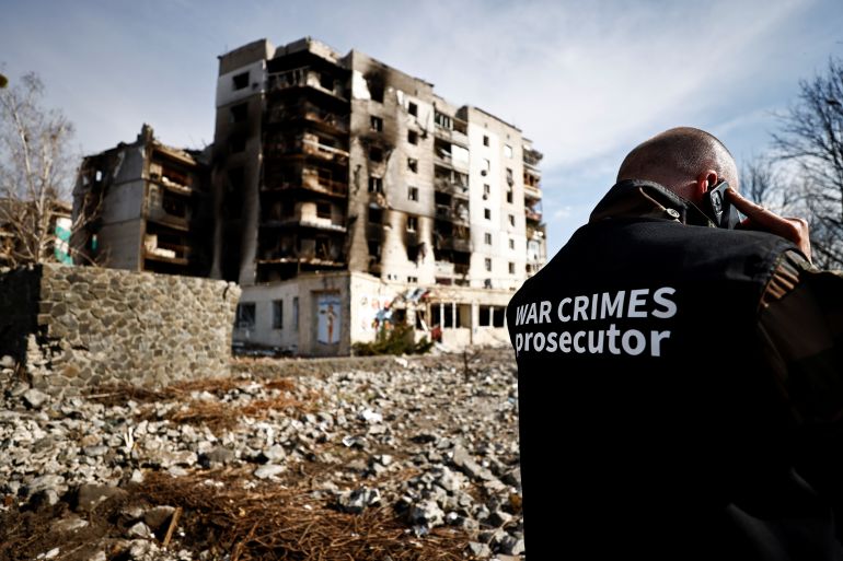 A war crime prosecutor speaks on the phone next to buildings that were destroyed by Russian shelling, amid Russia's Invasion of Ukraine, in Borodyanka, Kyiv on April 7