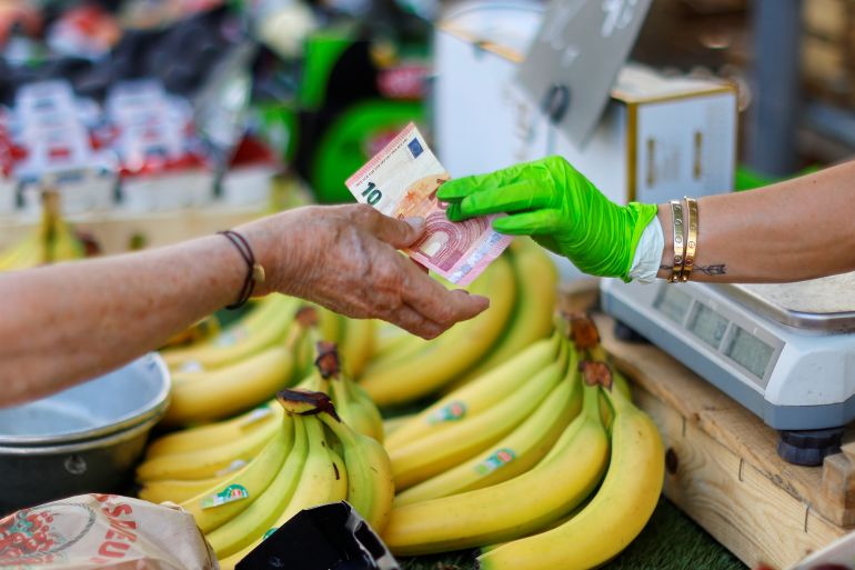 A shopper pays with a ten Euro bank note at a local market in Nice, France