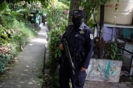 A police officer guards an access during a "Casa Segura" (Safe House) operation as part of the state of emergency to fight gangs, at the Altavista neighborhood in Tonacatepeque, El Salvador