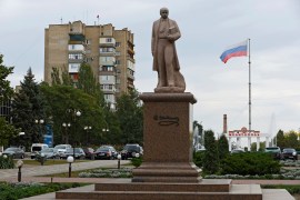 A monument to Ukrainian poet Taras Shevchenko with the Russian flag flying in the background in the Russian-controlled city of Melitopol in the Zaporizhia region [File: Alexander Ermochenko/Reuters]