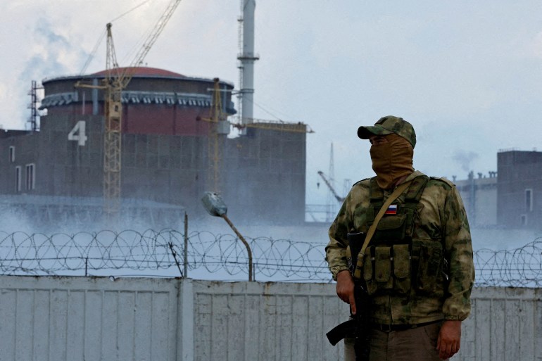 A serviceman with a Russian flag on his uniform stands guard near the Zaporizhzhia Nuclear Power Plant