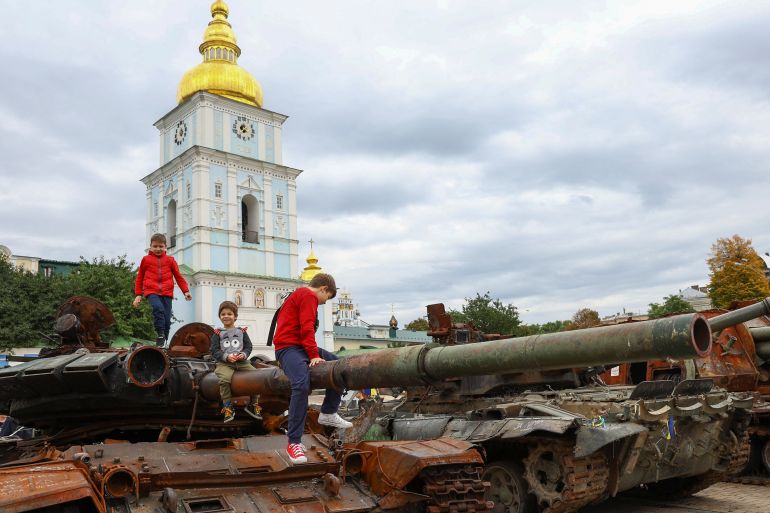 Children play on top of destroyed Russian military vehicles and weapons outside St Michael's Cathedral