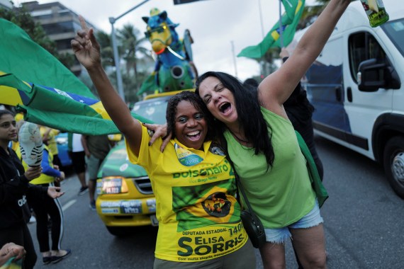 Two female Bolsonaro supporters in Brazilian colours of yellow and green celebrate outside his house after the presidential election went to a second round