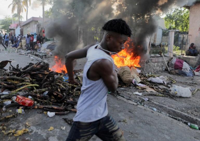 A man runs past a burning street barricade during a protest against the government and rising fuel prices, in Port-au-Prince