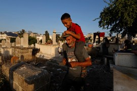 Omar Kuhail, 65, carries his grandson Mohammad Kuhail, seven, on his shoulders in the Sheikh Shaban cemetery where they live, in Gaza city. [Mohammed Salem/Reuters]