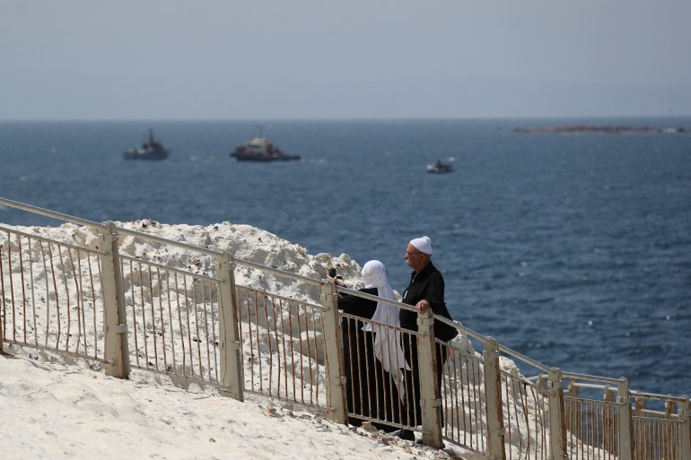 People walk as Israeli navy boats are seen in the Mediterranean Sea as seen from Rosh Hanikra, close to the Lebanese border, northern Israel May.