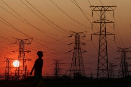 A resident walks past electricity pylons during frequent power outages from South African utility Eskom, caused by its ageing coal-fired plants, in Orlando, Soweto, South Africa [File: Siphiwe Sibeko/Reuters]