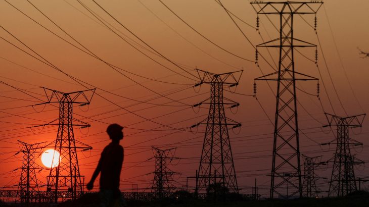 A local walks past electricity pylons during frequent power outages from South African utility Eskom, caused by its aging coal-fired plants, in Orlando, Soweto, South Africa, September 28, 2022. REUTERS/Siphiwe Sibeko/File Photo