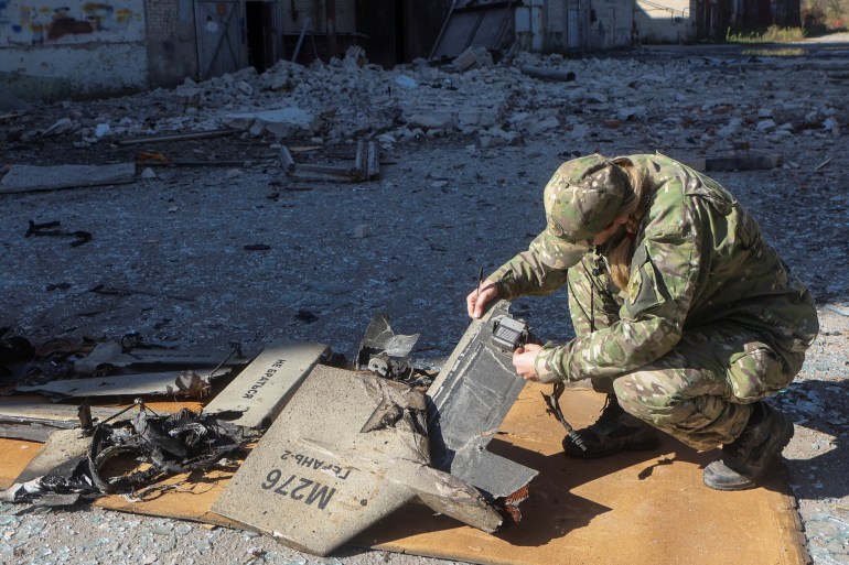 A police officer inspects parts of an unmanned aerial vehicle (UAV), what Ukrainian authorities consider to be an Iranian made suicide drone Shahed-136, at a site of a Russian strike on fuel storage facilities