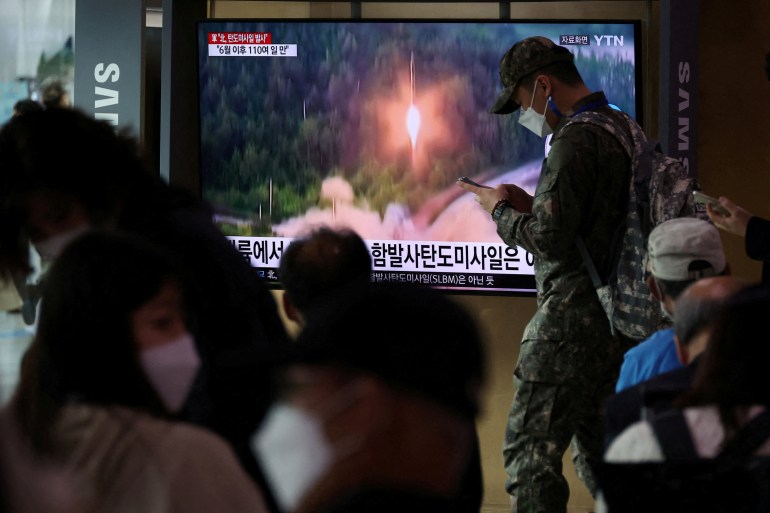 People watching a TV report on a North Korean missile launch on a large screen