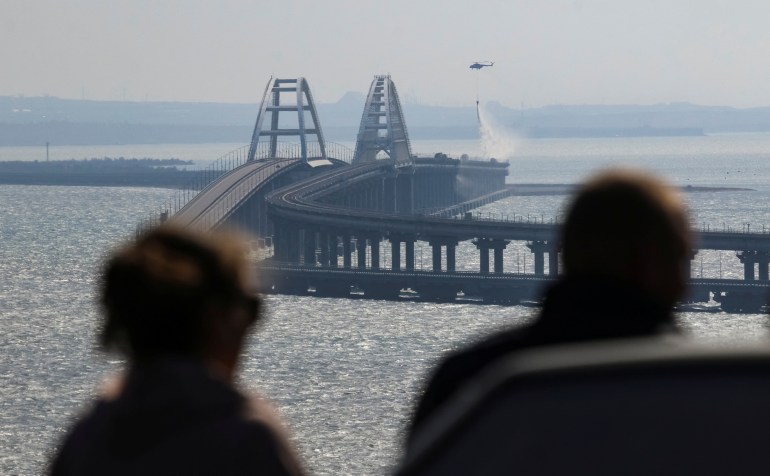 People watch fuel tanks ablaze on the Kerch bridge in the Kerch Strait, Crimea, October 8, 2022