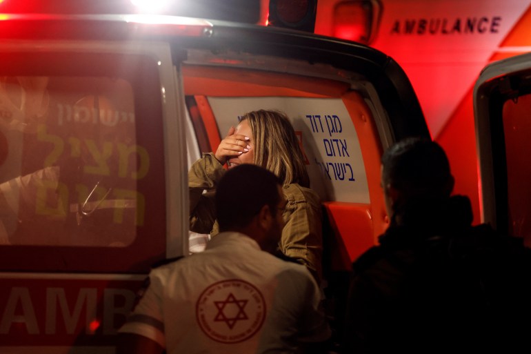 An Israeli soldier reacts as she sits in an ambulance following a shooting incident at a check point in East Jerusalem, Israeli police said on October 8