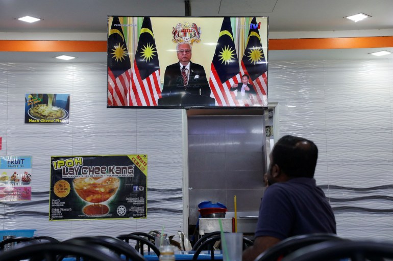 A restaurant customer watches Ismail Sabri announcing the dissolution of parliament on television