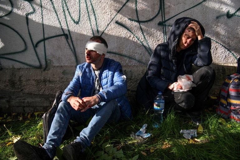 Injured people sit near a site of a Russian missile strike, amid Russia's attack on Ukraine, in Kyiv, Ukraine October 10