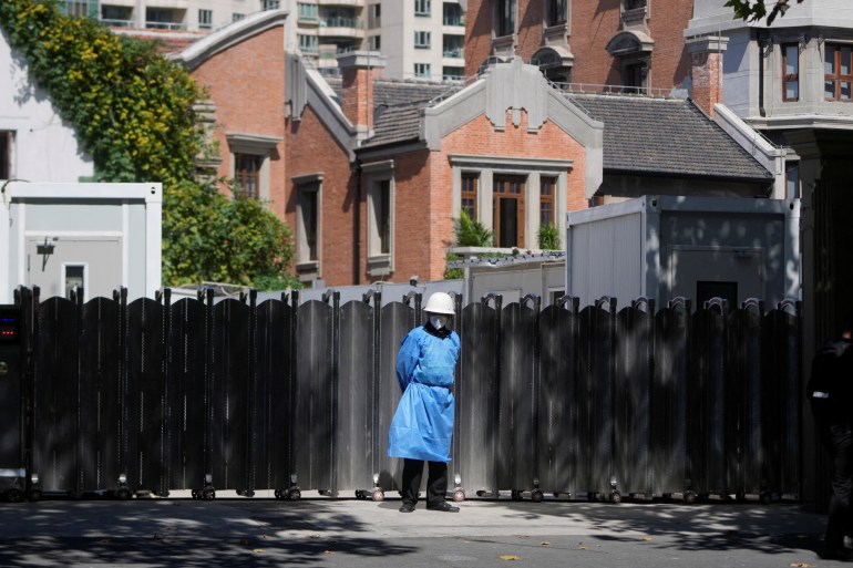 A security guard in protective overalls stands guard at a sealed residential area in Shanghai.