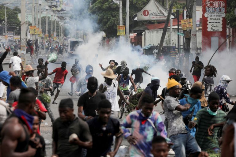 People run while police fire tear gas during a protest demanding the resignation of Haiti's Prime Minister Ariel Henry after weeks of shortages, in Port-au-Prince, Haiti October 10, 2022. REUTERS/Ralph Tedy Erol