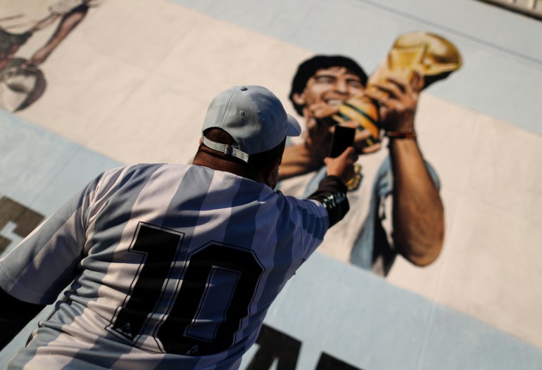 Arjantinli futbol süperstarı Diego Armado Maradona'nın bir hayranı, idolün 35. yıl dönümünü kutlarken bir duvar resminin fotoğrafını çekiyor. "yüzyılın hedefi"Arjantin, Buenos Aires'te Meksika'da oynanan 1986 Dünya Kupası'nda İngiltere'ye karşı 